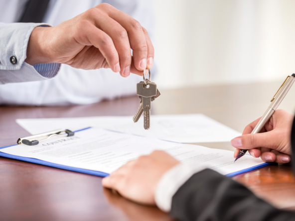 Realtor hands house keys as the buyer signs contract